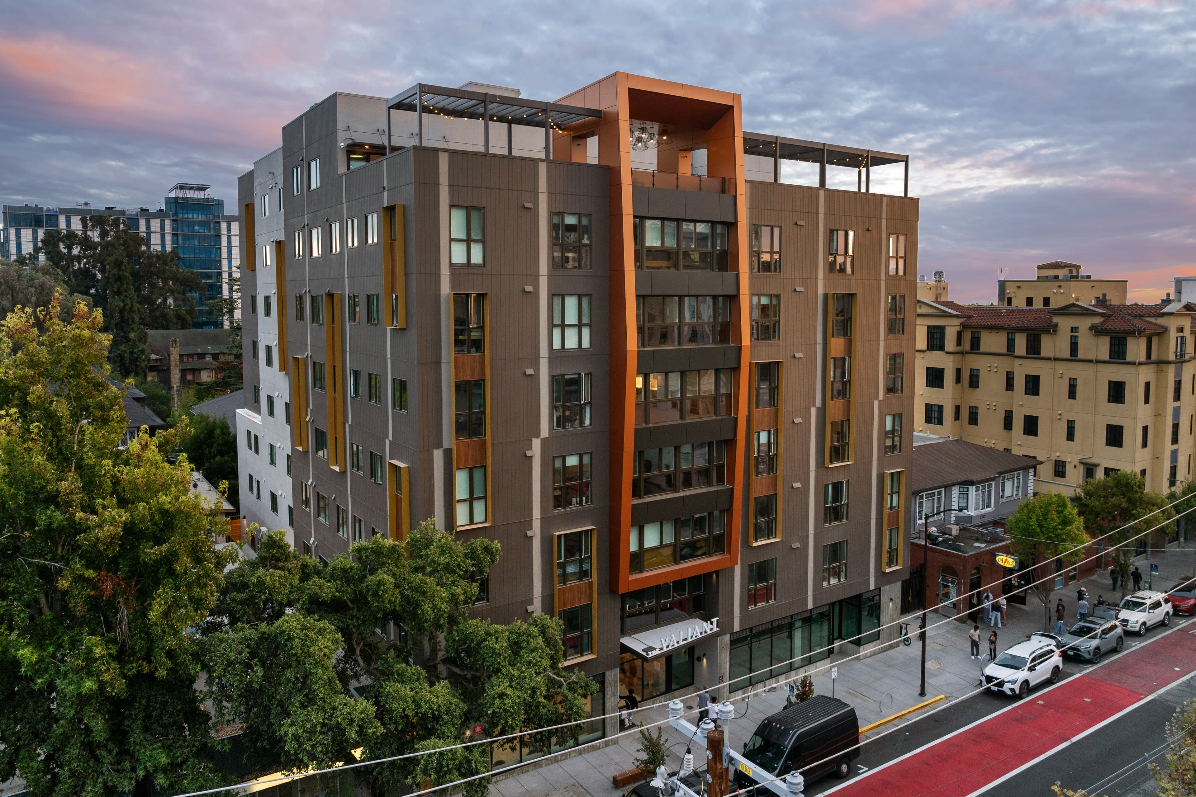 The Valiant at dusk, an eight-story building with bronze panels and orange accents on a Berkeley street